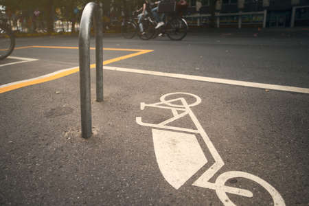 cargo bike symbol painted on asphalt at a dedicated parking slot at the city center of a big city with two moving female riders in background - modern city transport transformation conceptの写真素材