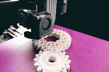 opblique view on process of 3D printing. Print head, bright pink print bed and white helical gears with visible infill and layer. copy space for text. selective focus. additive manufacturing conceptの写真素材