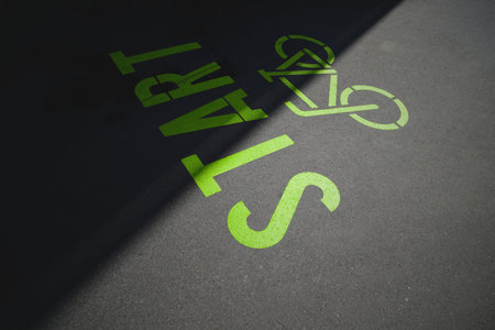 green bicycle symbol with lettering start painted on inner city asphalt surface. urban mobility and sport motivation concept. slogan for ecological traffic turn. selective focusの写真素材