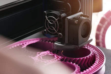3D printing of a planetary gear part from pink plastic filament in inspiring surrounding. selective...