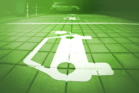 Electric vehicle parking symbol with green overlay on paved urban charging area. Eco-friendly mobility concept.の写真素材