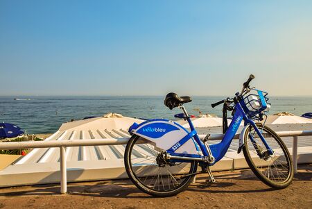 Nice, France - June 6, 2015: A blue bicycle at the rail near the beach in Nice city with blue sea and clear sky as backgroundのeditorial素材