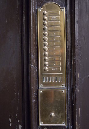 Vintage wall mounted doorbell with beige stone plate, brass buttons, speaker and nameplates