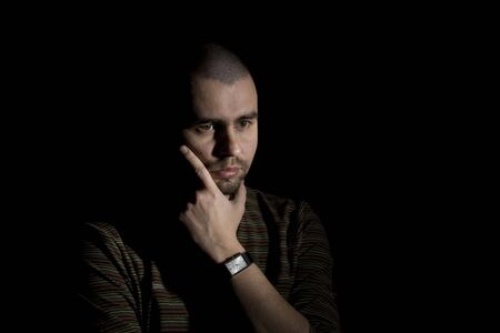Thoughtful man on black background in low key