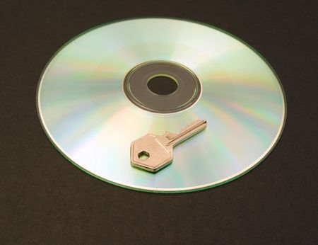 Photograph of a CD with small metal key. Dark background.の写真素材