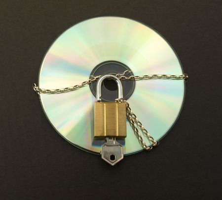 Photograph of a CD with chain, padlock and key. Dark background.の写真素材