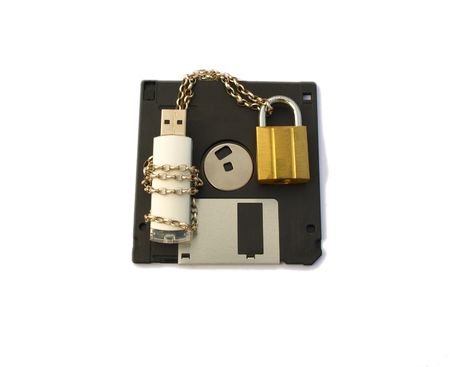 Computer data stick, wrapped with silver chain and padlocked with gold padlock, lying on a floppy disk. Isolated white background.の写真素材
