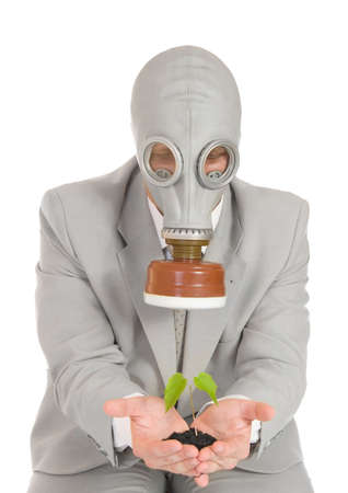 Businessman in gas mask holding green plant isolatedの写真素材