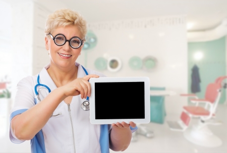 Mature doctor with funny glasses and tablet PC at medical officeの写真素材
