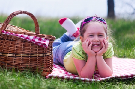Little smiling girl with picnic basket at forestの写真素材