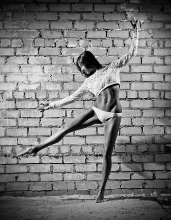 Dancing young woman on grey wall (monochrome version)の写真素材