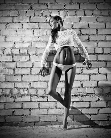 Sporty young woman on grey brick wall background (monochrome version)の写真素材