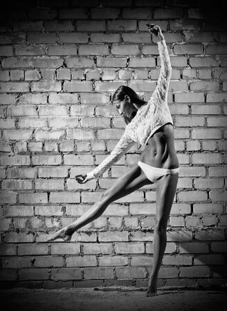 Young dancing woman on grey brick wall (monochrome version)の写真素材