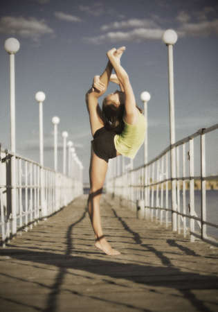 Young girl doing gymnastic exercises on the pier (ancient version)