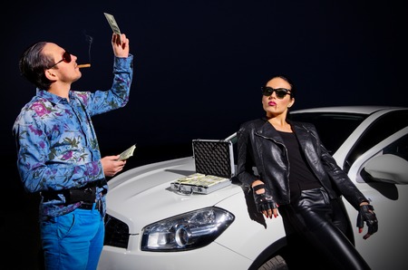 Two gangsters with dollars near the car
