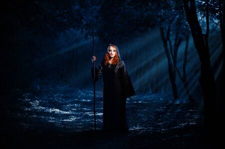 Young witch in night forest