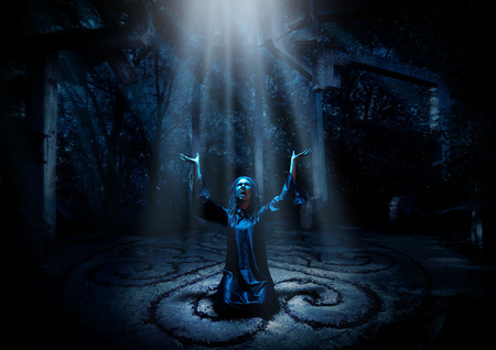 Scary witch in night forest with ray of light verの写真素材