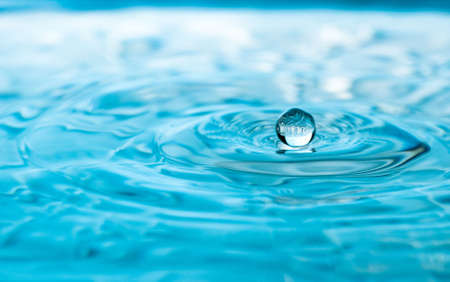 A water drop appears to float on the surface of the waterの写真素材