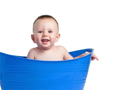 A cute baby boy playing in a blue plastic laundry basketの写真素材