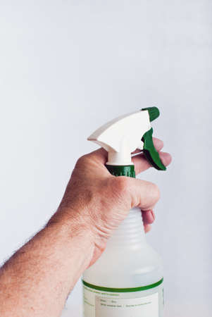 Male hand holding a spray bottle in the act of squirting it.の写真素材