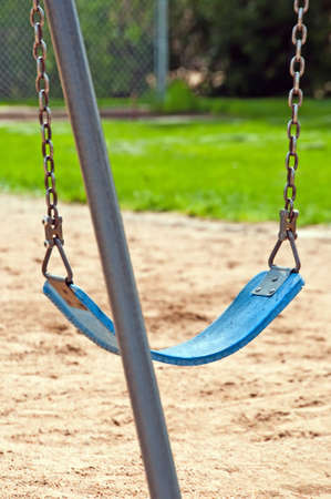A single park swing sitting idle waiting for joyful children to play on it.の写真素材