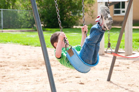 Little boy enjoying the swings at the city park.の写真素材