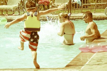 Young Parents enjoying time at the swimming pool with their children.の写真素材