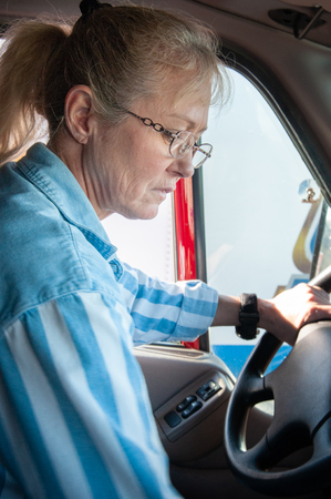 A woman truck driver shifting gears while driving a semi truck.