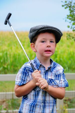 A cute little boy playing golf at home in the back yard.の写真素材