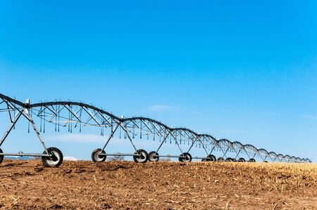 Irrigation sprinkler sits on the field after the harvest.の写真素材