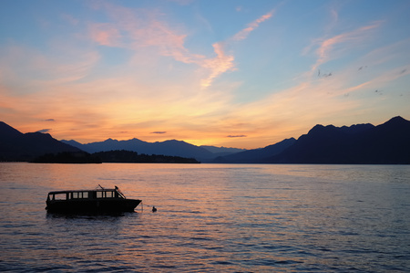 Small boat anchored in quite lake water before the dawn; Maggiore Lake, Italy.の写真素材