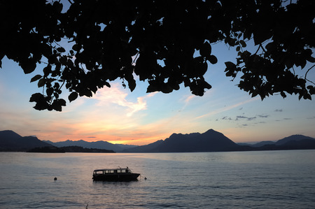 Small boat anchored in quite lake water before the dawn; Maggiore Lake, Italy.の写真素材