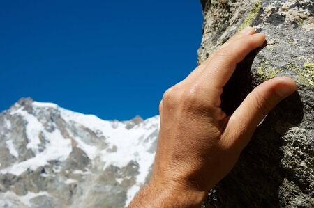Close-up of a climber's hand; in background the snowy high peak of Monte Rosa, Italy. Blue copy-space in the up-left area.の写真素材