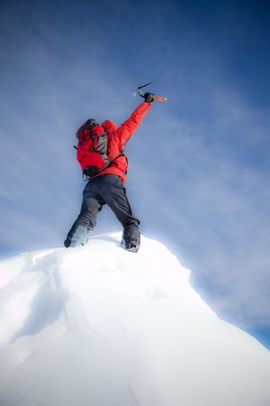 Mountaineer reaches the top of a mountain peak and expresses his joy. Vertical frame. Soft-focus versionの写真素材