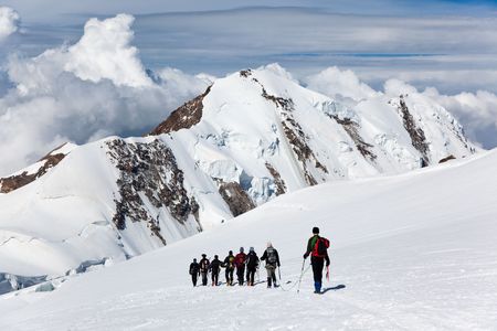 A large group of mountaneers walking on a glacier in a sunny day: in background the snowed peaks of Lyskamm (4550 mt) , Monte Rosa range, West Alps, Switzerland, Europe.の写真素材