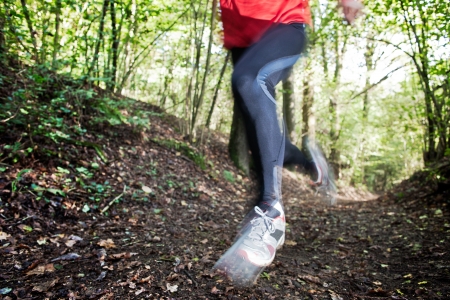 Male trail runner running in the forest on a trail  Red shirt and black pants  Summer season  Slight blur in runner to show motion  Horizontal composition の写真素材