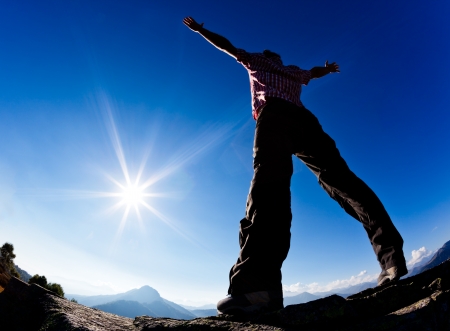 Man opens his arms in the sunshine against blue sky. Concept: freedom, success, energy, vitality.の写真素材