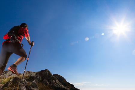 Skyrunner runs uphill along a mountain trail. Rear way, caucasian young man. Sunny summer day. West Alps, Europe.の写真素材