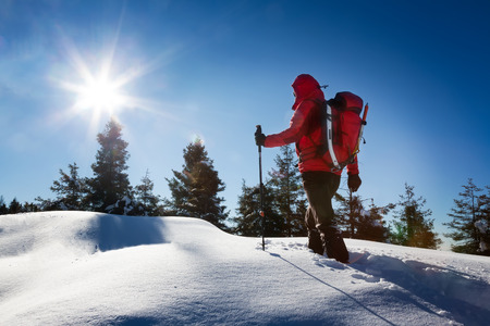 Winter hiking. A trekker, walking in the snow, takes a rest for admire the panorama. Sunny and frosty winter day. Italian Alps, Europe.の写真素材