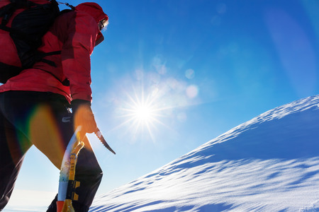 Concept: overcome challenges. Mountaineer faces a climb at the top of a snowy peak.の写真素材
