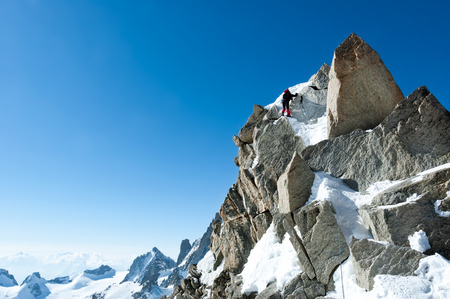 Climbing in Chamonix. Climber on the snowy ridge of Aiguille du Midi in Mont Blanc, France. Large copy-space on the left. Concepts: determination, concentration, effort, strength, team work.の写真素材
