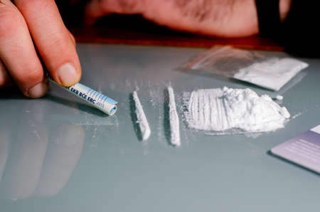 Man is about to snort cocaine with rolled up banknote. Narcotics concept.