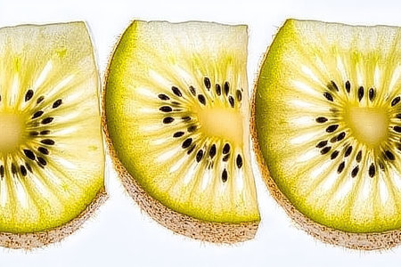 Three segments of a kiwi fruit are displayed, showcasing the vibrant yellow flesh and numerous black seeds.  The image's focus is on the intricate detail of the fruit's texture and the arrangement of seeds within the segments.の素材