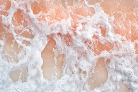 A photograph of the top view of ocean waves hitting the sand, with a light pink and orange beach and white foam in the foreground, and a blue water background, shot from above in a close-up, captured using a Hasselblad X2D camera. --ar 3:2 --v 6.1 Job ID: bfe210e6-c53c-43ba-b70f-8ceae8579087の素材