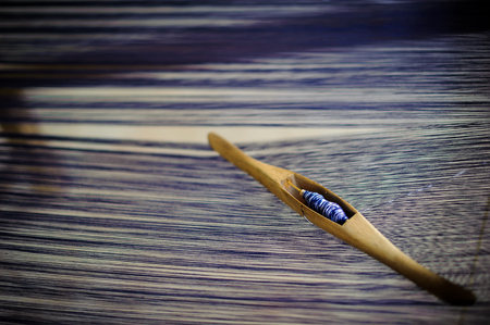 Original thai silk handwoven,Close up of wooden thread spinning with blue an white thread on loom.の写真素材