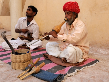 JAIPUR, INDIA - FEBRUARY 20  A snake charmer is playing the flute for the cobra sitting by the wall in the Fort Amber on February 20, 2010 in Jaipur, Indiaのeditorial素材