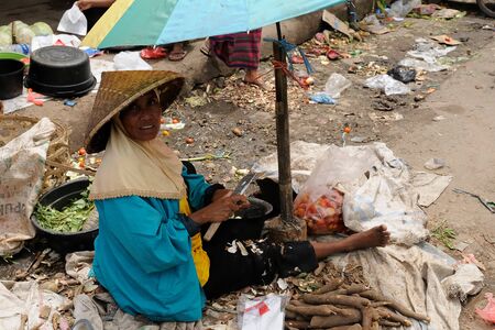 BIMA, SUMBAWA, INDONESIA - APRIL 14: Muslim woman trading in vegetables on the market in the Bima town on an island Sumbawa in Indonesia, Bima on April 14, 2011のeditorial素材