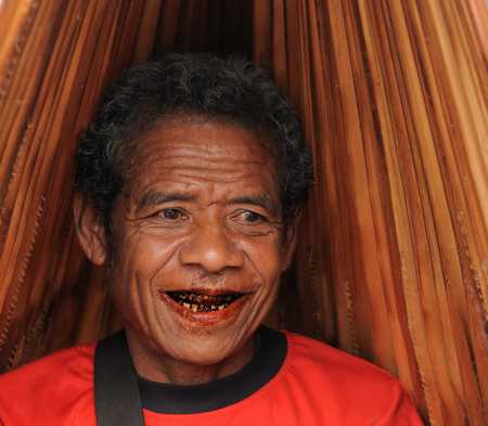 SOE, TIMOR, INDONESIA - APRIL 26: One of participants in the traditional exotic tribal market (pasar) with the umbrella made from the palm leaf in Indonesia on the Timor island. Soe on April 26, 2011.One of participants in the traditional exotic tribal maのeditorial素材