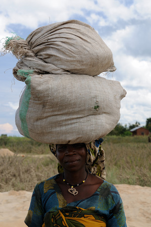 IKOLA, TANZANIA - MAY 07: African woman carrying on her head two bags of grain in the Lake Tanganyika in Tanzania, Ikola in May 07, 2013のeditorial素材