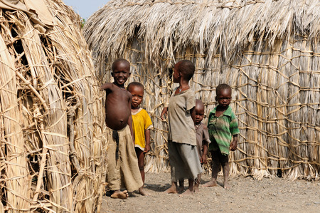 KOMOTE, KENYA - JULY 12: Group of children from the ElMolo tribe playing around traditional round houses from grass in the village Komote in Kenya, Komote in July 12, 2013のeditorial素材